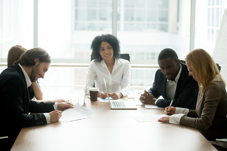 Businessman and businesswoman signing contracts at group multiracial meeting